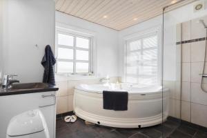 a white bathroom with a tub and a sink at 2219-Ringkobing-Frans-Julius-Vej-2 in Søndervig +26 photos