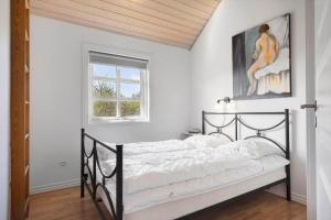 a bedroom with a black bed with a painting on the wall at 2219-Ringkobing-Frans-Julius-Vej-2 in Søndervig