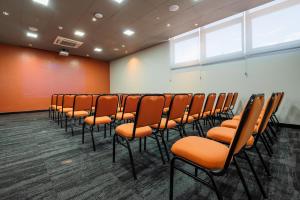 a row of chairs in a room with orange walls at Ibis Porto Alegre Assis Brasil - Estacionamento Gratuito para hospedes in Porto Alegre