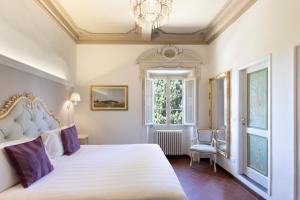a bedroom with a large white bed and a chandelier at Art Hotel Villa Agape - Place of Charme in Florence