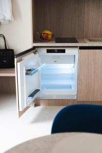 an empty kitchen with an open refrigerator in a counter at TWILL Apartments in Brno