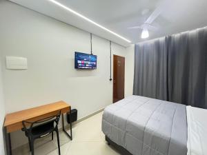 a bedroom with a bed and a desk and a tv at Hostel Pouso Gru - Translado Aeroporto Gru grátis in Guarulhos