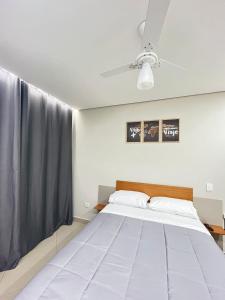 a bedroom with a large white bed with a ceiling fan at Hostel Pouso Gru - Translado Aeroporto Gru grátis in Guarulhos