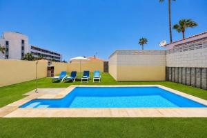 a swimming pool with two blue chairs in a yard at DUPLEX C9 con PISCINA PRIVADA in Callao Salvaje