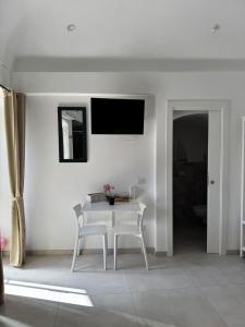 a white dining room with a table and two chairs at Stanza dei Desideri in Peschici