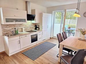 a kitchen with white cabinets and a table with chairs at Am Pappelweg - ABC620 in Hohen Viecheln
