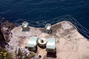 a table and chairs on a boat near the water at Albergo La Conca Azzurra in Conca dei Marini
