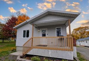 a small white house with a wooden porch at Chalet #10 - Spa & Fireplace in Cap-Saint-Ignace