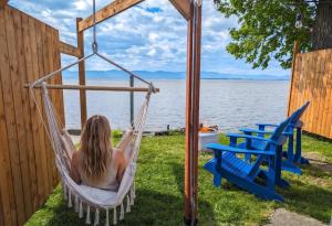 a woman sitting in a hammock by the water at Chalet #10 - Spa & Fireplace in Cap-Saint-Ignace +29 photos