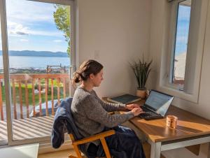 a woman sitting at a table with a laptop at Chalet #10 - Spa & Fireplace in Cap-Saint-Ignace