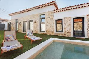a backyard with a pool and two chairs and a house at Vila Santa Luzia 2 in Fátima
