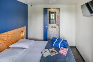 a bedroom with a bed with a book on it at Eklo Hotels Lille in Lille