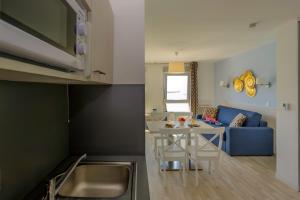 a kitchen and living room with a table and a blue couch at Résidence Goélia Le Phare in Le Tréport