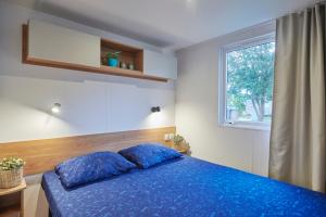 a bedroom with a blue bed and a window at Siblu Camping Meerwijck in Kropswolde