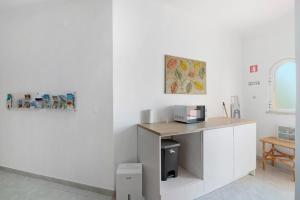 a white kitchen with a counter and a table at South Star Guesthouse in Quelfes