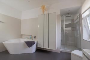 a white bathroom with a tub and a shower at Gästehaus am Lausitzring in Poley +31 photos