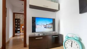 a living room with a flat screen tv and a clock at Apartamento Aguamarina con terraza in Chiclana de la Frontera