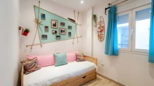 a bedroom with a bed with pink and blue pillows at Apartamento Aguamarina con terraza in Chiclana de la Frontera +9 photos