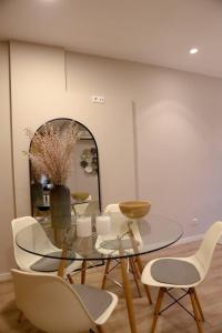 a dining room with a glass table and white chairs at Casa Ponte de São Gonçalo in Amarante +17 photos