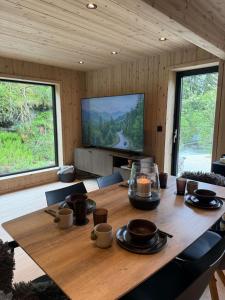 a dining room with a wooden table and a television at By the River in Vinje