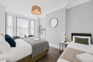 a white bedroom with two beds and a mirror at Rockland Retreat - Near Crosby Beach & Liverpool in Waterloo
