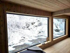 a room with a large window in a cabin at By the River in Vinje