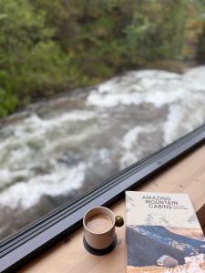 a cup of coffee sitting on a window sill next to a book at By the River in Vinje