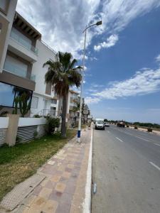 a street with a palm tree on the side of the road at Pearl Beach Apartment in Monastir