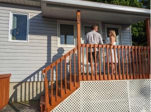 a man and woman standing on a porch of a house at Chalet Studio #12 - Relaxing getaway with Wifi & AC in Cap-Saint-Ignace