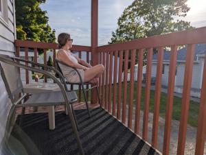 a woman sitting in a chair on a porch at Chalet Studio #12 - Relaxing getaway with Wifi & AC in Cap-Saint-Ignace