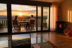 a man and woman sitting at a table on a balcony with a sunset at El Triskel de Chumbea- Confort y naturaleza en la Sierra de Béjar in Navalmoral de Béjar