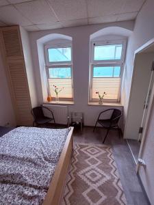 a bedroom with a bed and two windows and a rug at Pension Zur Taube in Bautzen