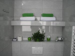 ein Badezimmer mit weißen Handtüchern und einer Pflanze auf einem Regal in der Unterkunft Eva Luxury Rooms & Apartments in Plitvička Jezera