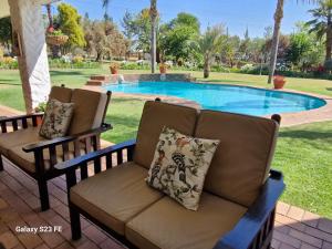 a couch sitting in front of a swimming pool at Villa Sardinia Guest House in Midrand