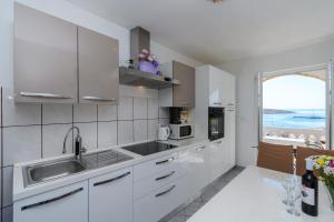 a kitchen with white cabinets and a sink and a window at Apartments Albina in Lopar