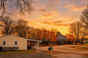 a building with a bench and a barn with a sunset in the background at Skylark Motel by OYO in Bedford
