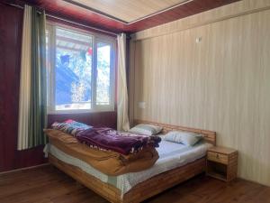 a small bed in a room with a window at beheney Homestay gondhla in Kyelang