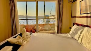 a bedroom with a bed and a window with a couch at Dahabiya Queen Tyi II in Luxor +5 photos