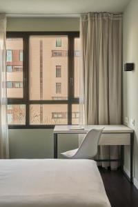 a bedroom with a bed and a desk and a window at RICE Bulevar in Burgos
