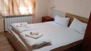 a bedroom with a bed with white sheets and pillows at Вила Стряма in Hisarya