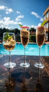 three wine glasses sitting on a table next to a pool at Westside Hotel Kitale in Kitale