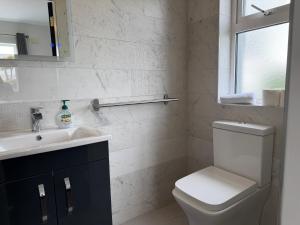 a bathroom with a toilet and a sink and a window at Number 6 Westpark Spanish Point in Spanish Point