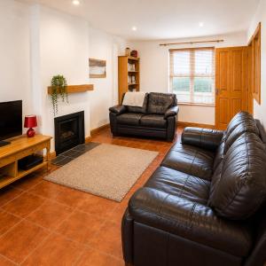 a living room with a leather couch and a fireplace at Kilkee Townhouse by Trident Holiday Homes in Kilkee