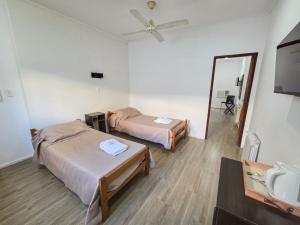 two beds in a room with a mirror and a sink at Hotel Milton in La Paz
