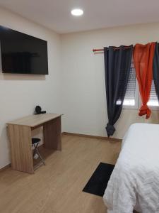 a bedroom with a bed and a desk and a television at HcHOME in Algeciras