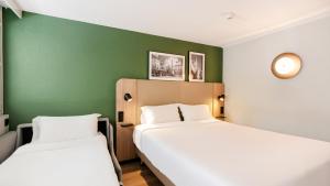 two beds in a room with green walls at Campanile NATURE - Metz Technopôle in Metz