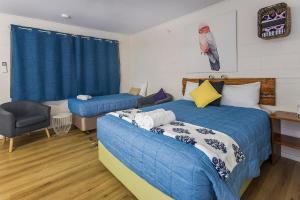 a bedroom with two beds and a chair in it at Kilcoy Motel in Kilcoy +86 photos