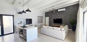 a white living room with a couch and a tv at Sage & Salt in St. Helena Bay
