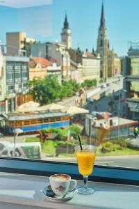 a glass of orange juice and a cup of coffee on a table at Hotel Pupin Novi Sad in Novi Sad