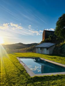 a swimming pool in the middle of a field with a building at Angrill in Lladurs